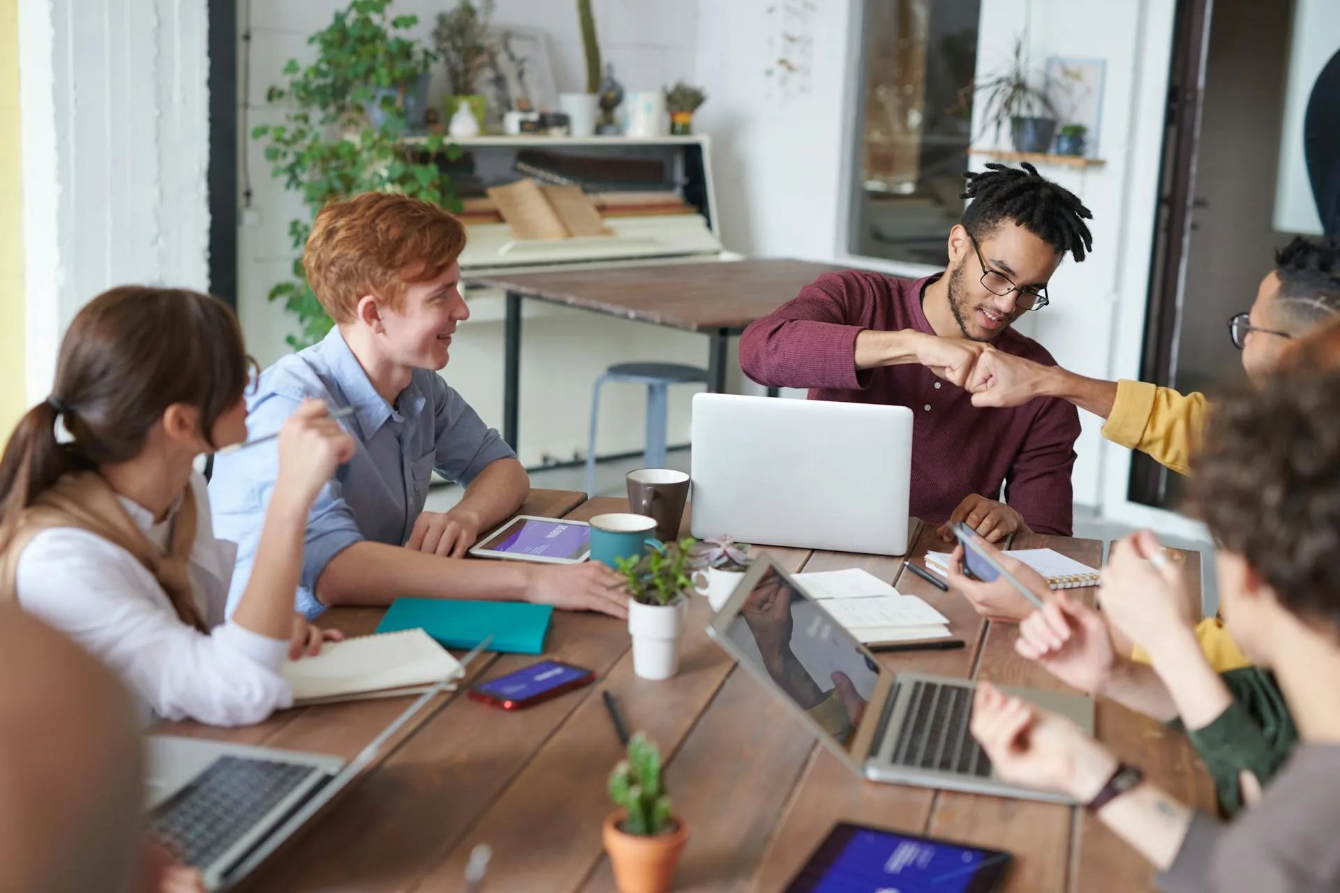 Personen sitzen um einen Tisch mit Tablets und Laptops